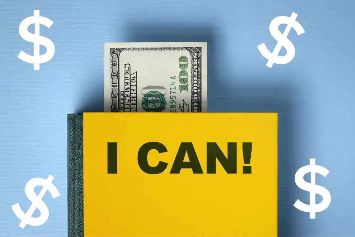Money protruding from a self-help book with 'I CAN' on the cover.